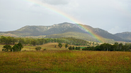 Rural landscape with rainbow over the mountain on a rainy day. Scenic Rim, Queensland, Australia.
