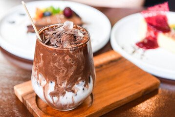 cocoa drink and chocolate - tasty milk shake with ice cocoa in glass on wood background