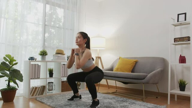 Asian women practice squats on a training. Attractive female making yoga pose in living room at home. wellness concept.