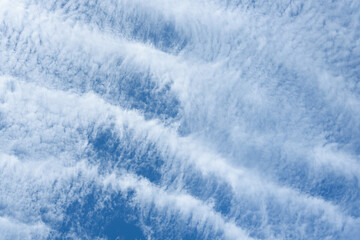 Blue sky and thin striped white cloud layer as a nature background
