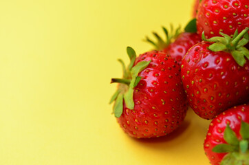 a pile of ripe fresh red strawberries lies right on the yellow background with a copy space
