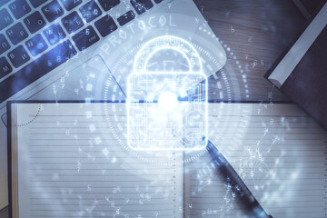 Double exposure of lock hologram drawing over study table background with computer. Concept of data security. Top view.