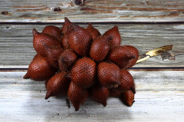 Bunch of Salacca or snake fruit on the wooden table. Famous tropical fruit in Asia. Sweet and sour tasty fruit with high vitamin and nutrition. 