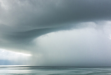 Fototapeta premium A rain storm in Daytona, Florida pours water over the Atlantic Ocean during a grey and overcast day by the beach.