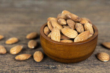Almonds seed in wooden bowl on wooden table background.