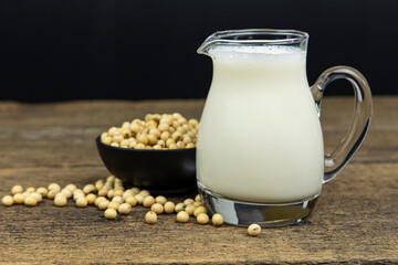A glass of soymilk with soybeans on wooden table background.