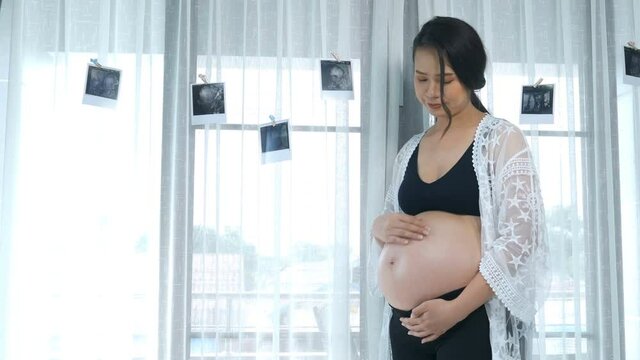 pregnant woman with ultrasound photo and pat her pregnant belly