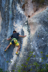 Obraz premium A strong man overcomes a difficult climbing route on a natural terrain.