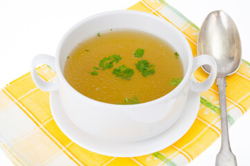 Transparent meat broth with herbs in white plate