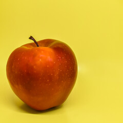 Red juicy apple on a yellow background. Close-up. Healthy food concept. Space for text.