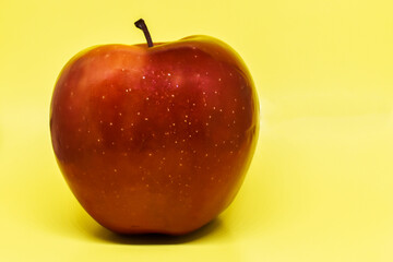 Red juicy apple on a yellow background. Close-up. Healthy food concept. Square image orientation. Space for text.