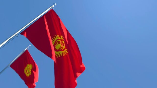 The national flag of Kyrgyzstan is flying in the wind against a blue sky