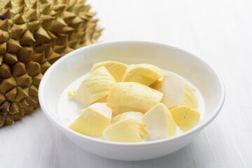 Thai dessert, sliced durian fruit with coconut milk in a bowl on white table background