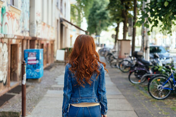 Obraz na płótnie Canvas Young woman walking away down an urban street