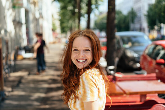Cute happy young woman turning to grin at camera