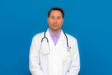 A male doctor with a stethoscope smiling a clipboard while standing in a clinic. on light blue background