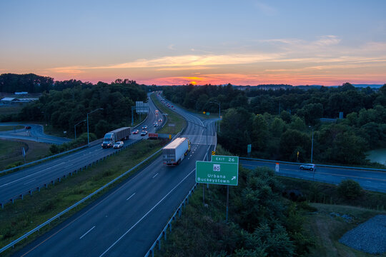 The sun sets over Interstate 270 in Urbana, Frederick County, Maryland. Two tractor trailers pass in opposite directions.