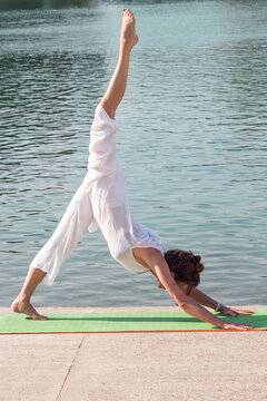 adult woman practice yoga summer morning by lake