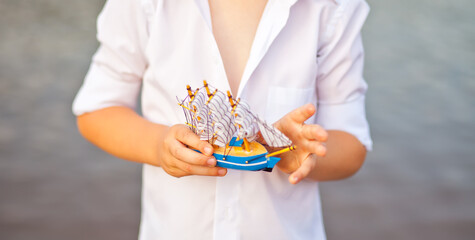 Boy holding toy boat, model of the ship