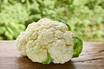 A whole head of cauliflower on a rustic wooden table.