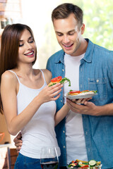 Portrait image of beautiful happy amazed young amorous couple eating together some fresh food, indoors. Love, romantic, young family and healthy diet eating concept picture. Square composition.