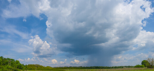 closeup huge comulus clouds with rain above a green prairie