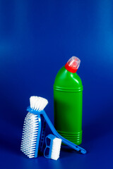 green Bottle with detergent powder and brushes on blue background, space for text.