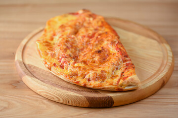 Calzone, Italian traditional food. Served on wooden board over rustic wooden table background closeup.