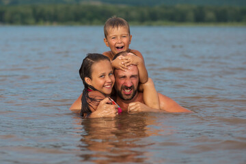 Happy family concept. Father, son and daughter playing in water 