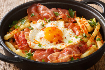 Huevos Rotos Recipe: Spanish Broken Eggs with potato and jamon close-up in a plate. Horizontal