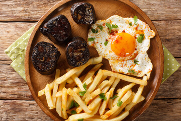 Huevos Rotos Recipe: Spanish Broken Eggs with potato and blood sausage close-up in a plate on the table. Horizontal top view from above