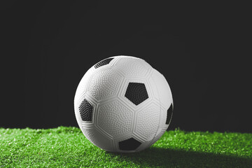 Fototapeta na wymiar Soccer ball on green field against dark background