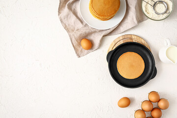 Frying pan with tasty pancakes and ingredients on white background