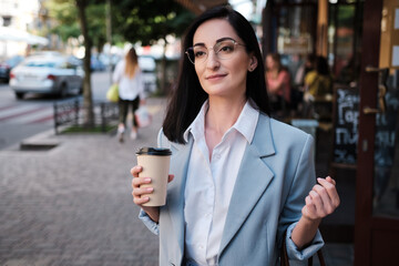 smiling businesswoman holding cofee in urban background - 368181790