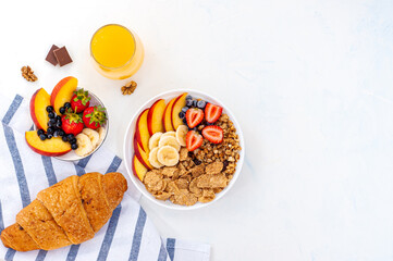 Light summer breakfast muesli with fruits, berries, juice and croissant on a light background. Flatly.
