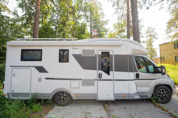 A white mobile home is parked in the woods. Caravan for life and family road travel. No people.