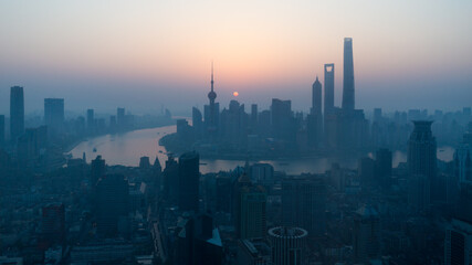 Sun rising above the Shanghai skyline. With skyscrapers and Huangpu River.