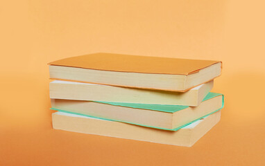 A stack of four books with colored covers is laid out on a uniform background