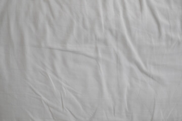 Fototapeta na wymiar White delicate soft background of fabric or bedding sheet in dark room.