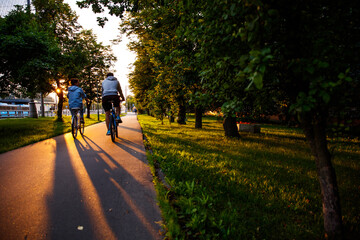 Couple riding bicycles on sidewalk with sunset background