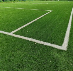 Fototapeta premium Empty soccer Football on Corner kick line of ball and a soccer field, football field, background texture. Green bright grass is grown for the football field. White stripe on the green soccer field.