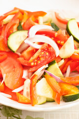 Vegetarian food. Salad of tomatoes, cucumbers, sweet peppers and onions drizzled with vegetable oil. Salad in a white plate.