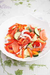 Vegetarian food. Salad of tomatoes, cucumbers, sweet peppers and onions drizzled with vegetable oil. Salad in a white plate.
