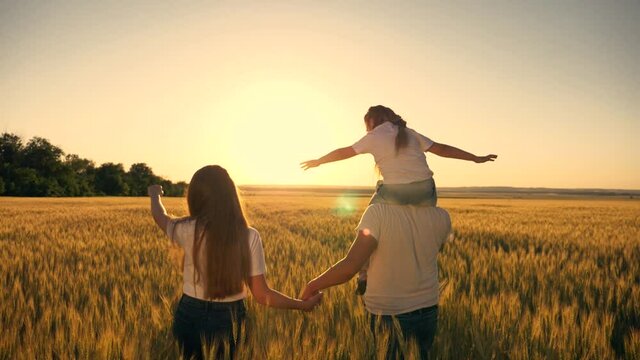 Happy family, people. Family lifestyle. Beautiful sunset on a wheat field. A happy child on the shoulders of a caring father. A walk in the Park.
