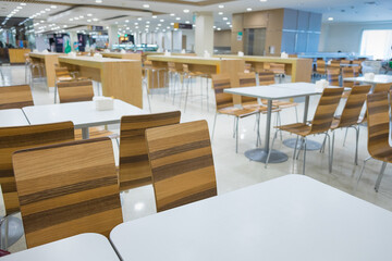 Interior of white table and wooden table on food court in shopping mall. - obrazy, fototapety, plakaty