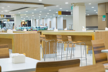 Interior of white table and wooden table on food court in shopping mall.