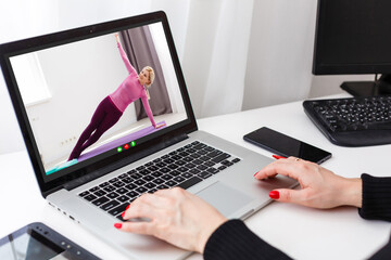 Woman watching sport training online on laptop. Fitness and sport blog.