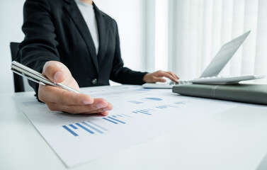 The hands of a male businesswoman are analyzing and calculating the annual income and expenses in a financial graph that shows results To summarize balances overall in office