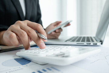 The hands of a male businesswoman use the calculator are analyzing and calculating the annual income and expenses in a financial graph that shows results To summarize balances overall in office