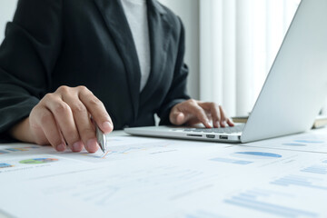 Obraz premium The hands of a male businesswoman are analyzing and calculating the annual income and expenses in a financial graph that shows results To summarize balances overall in office